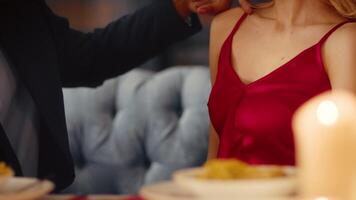 A young, diverse couple shares a tender moment during dinner at a restaurant. They display affection as they enjoy their meal, surrounded by a warm and inviting atmosphere. video