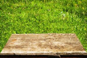 empty old brown table on green grass background. photo