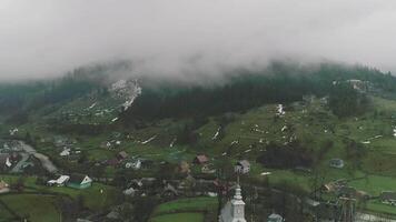Small mountain village with cute chapel and little houses in valley near river, village view and mountain scenery, countryside charming, peaceful traditional, idyllic river view video