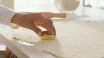 In a warm, inviting kitchen, a young African American woman is skillfully cutting cookie shapes from rolled-out dough. She enjoys baking and creating delicious treats. video