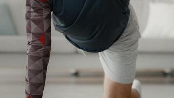 A young man exercises in a bright living room, focusing on his push-up routine. He wears athletic clothing and displays determination while engaging in his workout. video