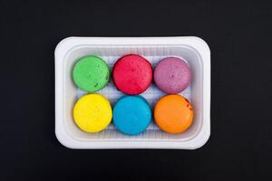 colored macaroons on a white plate on a black background photo