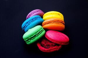 Sweet and colorful french macaroons or macaron on black background. photo