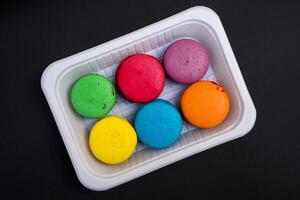 colored macaroons on a white plate on a black background photo