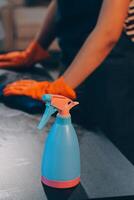 A woman is using a spray bottle to clean a table photo