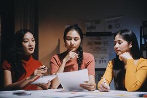 Three women sitting at a table with papers photo