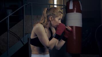 Woman boxer boxing with shadows in a semi-dark room practicing punches shadow boxing, slow motion. for motivation, success video