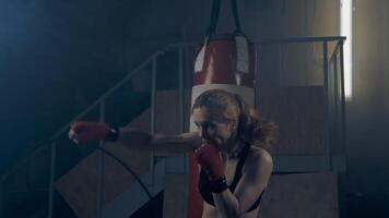 Strong and confident woman in athletic form practicing combat strikes with a shadowy opponent video