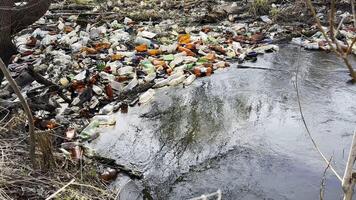 Dirty river is polluted with many plastic bottles. A lot of trash is dumped in open and freely available places at nature. Global environmental pollution problem. Concept of ecological disaster photo