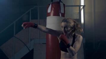 Woman fighter in a dark room practicing shadow boxing throws strong fast punches with back light in slow motion , 4k video