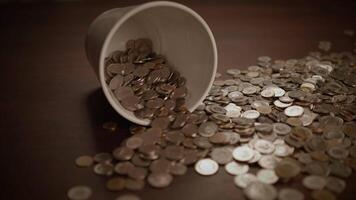 Coins spilled from a cup onto a wooden surface, creating a scene of disarray and abundance video