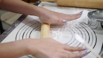 Hands rolling out gyoza dough on a floured surface with precision, showcasing the process of crafting Japanese dumpling wrappers with kitchen tools like a rolling pin and sifter in the background video