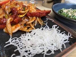 Spicy sliced chicken fillet with hot garlic sauce with vegetables and fried glass noodle and a bowl of seaweed salad photo