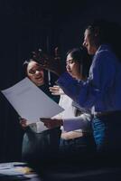 Three women standing in front of a sheet of paper photo