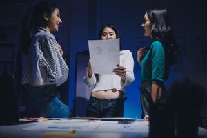 Three women standing around a table with a piece of paper photo