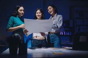 Three women standing in front of a computer with a piece of paper photo