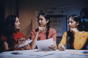Three women sitting at a table with papers photo