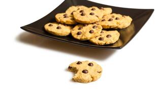 Chocolate chip cookies on a black plate composition photo