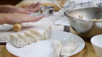 Hands rolling out gyoza dough on a floured surface with precision, showcasing the process of crafting Japanese dumpling wrappers, with kitchen tools like a rolling pin and sifter in the background video