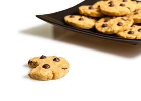 Detail of chocolate chip cookie with a bite and pile of cookies in a plate on the background photo