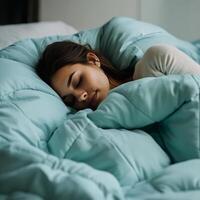 woman sleeping peacefully under cozy aqua blue comforter, exuding tranquility and comfort in serene bedroom setting photo