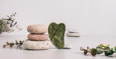 Jade gua sha massager and pebbles on table web banner photo