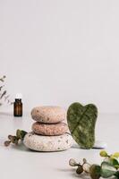 Jade gua sha massager, pebbles and spa items on table vertical view photo