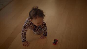 A Crawling Baby Happily Engaged with a Colorful Toy Car on the Wooden Floor, Exploring video