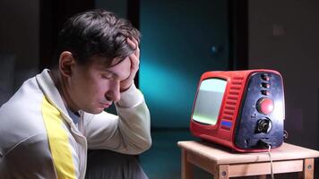 a man fell asleep while watching an old tube TV. There is white noise on the TV screen video