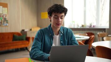 Smiling Caucasian man male teenage happy guy student schoolboy pupil modern technology service study exam using laptop computer e-learning learn studying online internet education in school university video