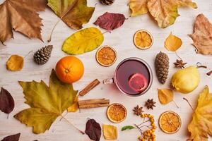 Autumn leaves, oranges, cinnamon, and tea on a white table photo