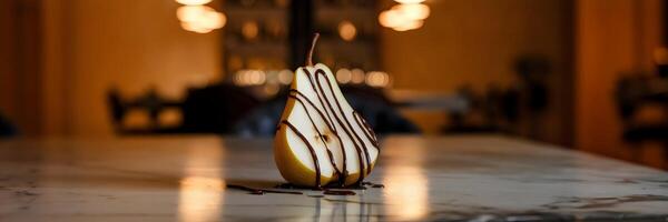 Pear half drizzled with dark chocolate on marble surface photo