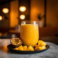 Glass of mango passion fruit juice with fruit on black plate photo