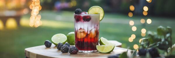 Blackberry and lime iced tea in frosted glass with garden party background photo