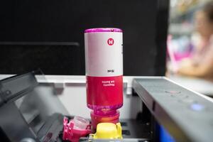 Closeup Refilling ink into a red ink tank printer at office. Cartridges and containers of continuous ink supply system. photo