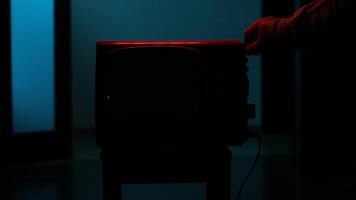 Hand turning on old analog television set in dark room video