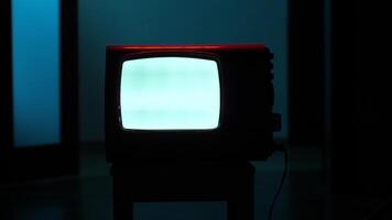 Old analog television set displaying static white noise in dark room video