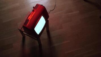 Old red television set displaying static on wooden stool video
