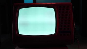 Old red television set displaying static noise in dark room video