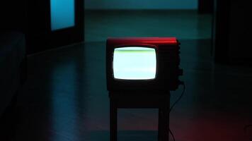 Old analog television showing white static noise in dark room video