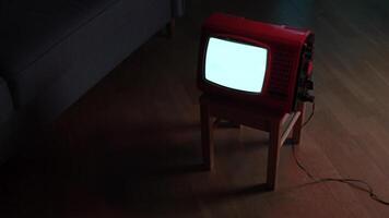 Vintage red television set displaying static on wooden stool in dark room video
