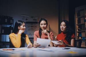 Three women sitting at a table with papers photo