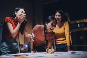 Three women laughing and smiling while working on a project photo