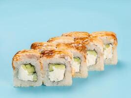 Studio photography of Philadelphia Roll of velvety cream cheese and cucumber wrapped in perfect seasoned sushi rice and fresh unagi smoked eel. Isolated on solid light blue background photo