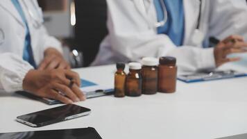 Two doctors sitting at a table with bottles and tablets video
