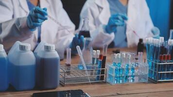 Two people in lab coats working on a table with test tubes video