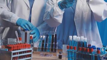 Two people in lab coats and gloves are working on a table video