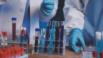 Two people in lab coats and gloves are working on a table video