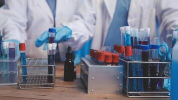 Two people in lab coats are working on a table with test tubes video