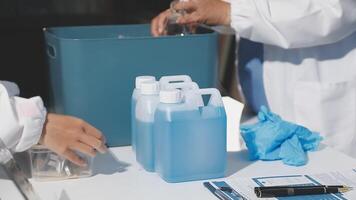 Two people in lab coats are working on a table with bottles and containers video